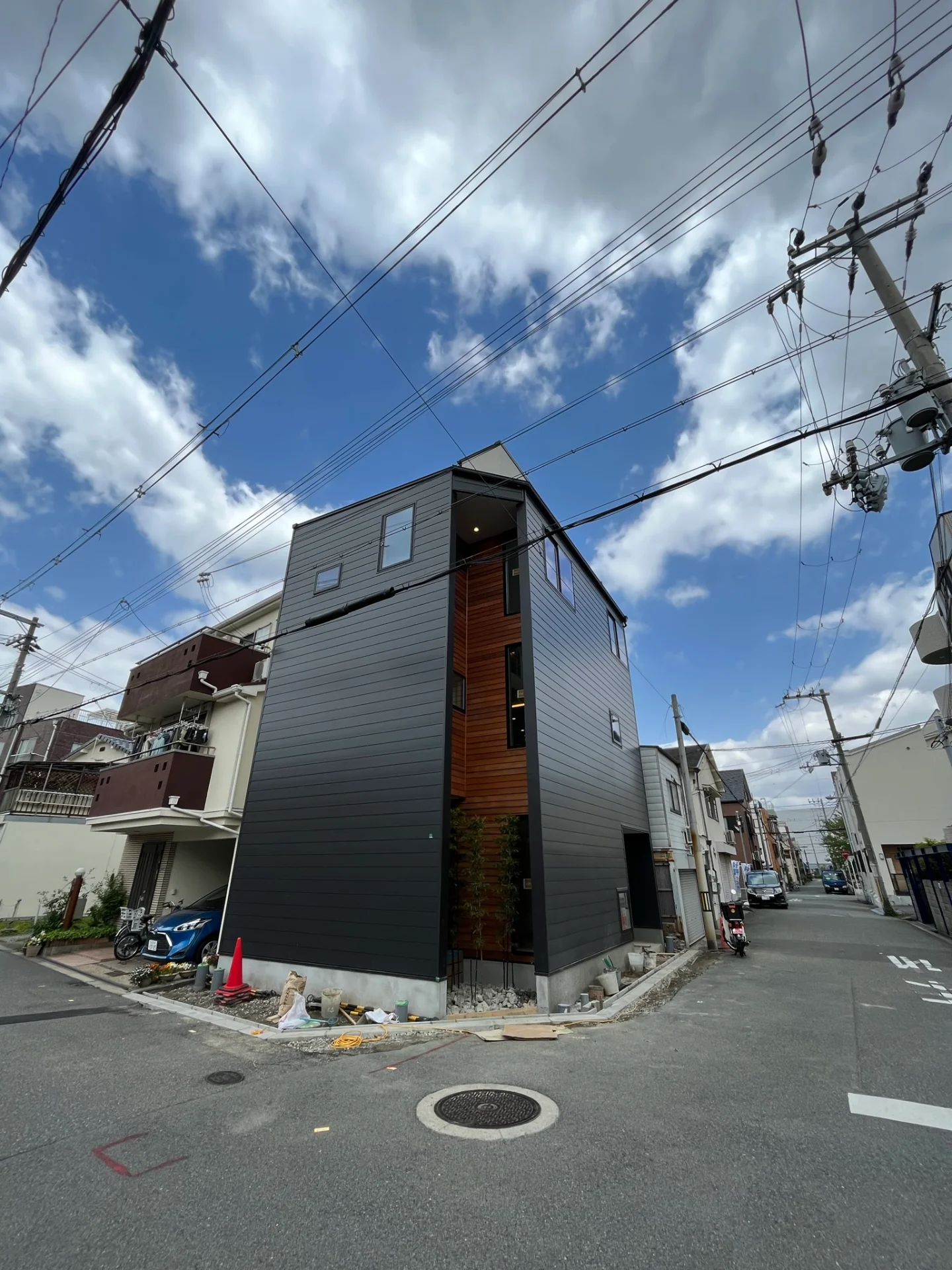 二枚の壁のスリットから灯りがこぼれる街角の住宅
